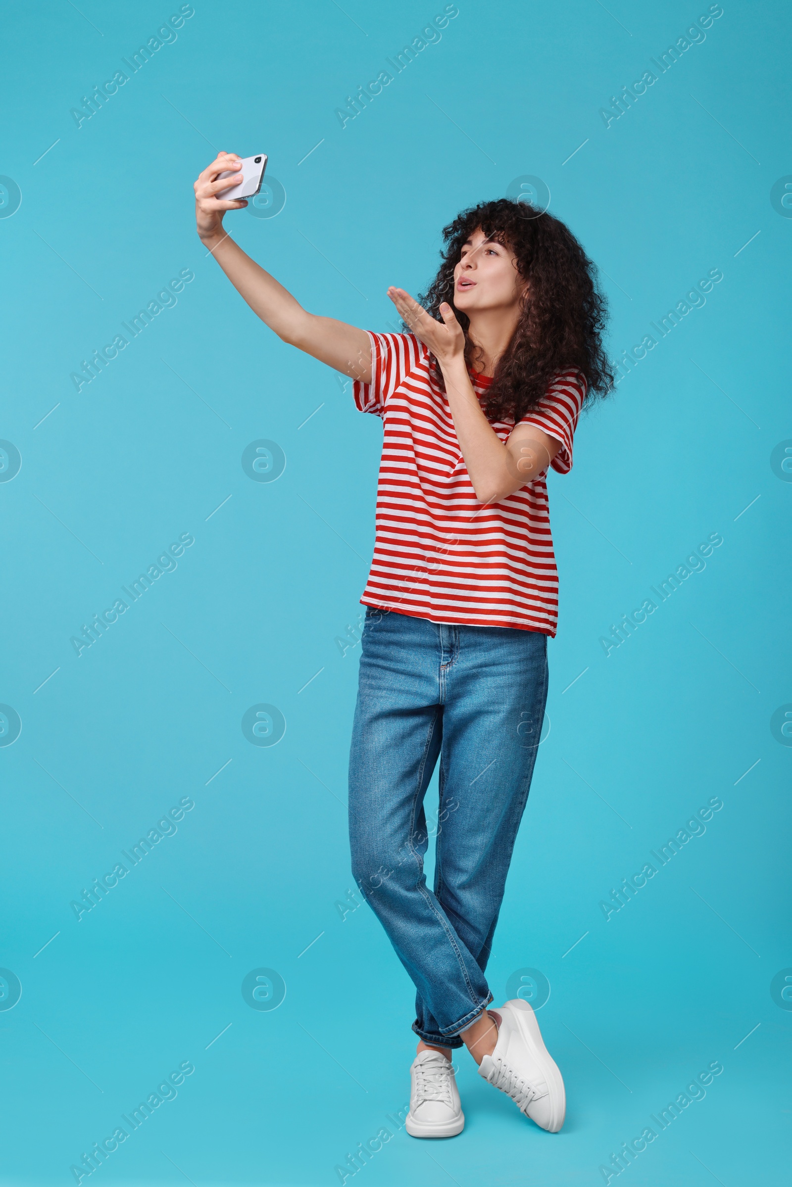 Photo of Beautiful young woman taking selfie on light blue background