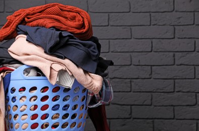 Photo of Laundry basket with clothes near black brick wall. Space for text