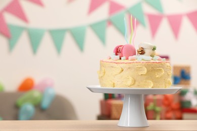 Photo of Delicious cake decorated with macarons and marshmallows on wooden table in festive room, space for text