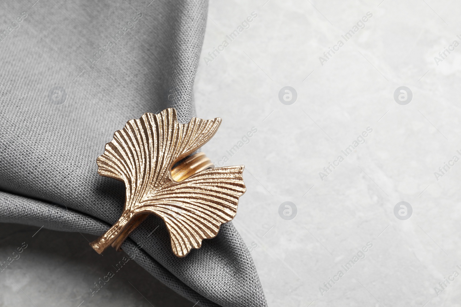 Photo of Fabric napkin with decorative ring on light gray background, closeup. Space for text