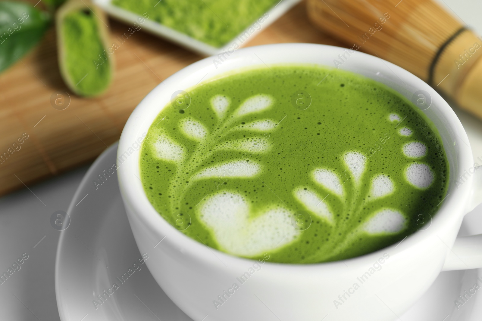 Photo of Delicious matcha latte in cup on white table, closeup