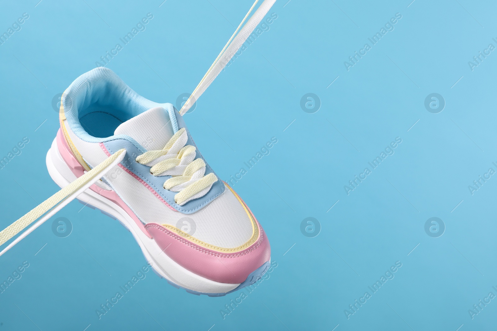 Photo of Stylish sneaker on light blue background. Space for text