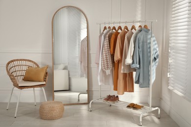 Modern dressing room interior with stylish clothes, shoes and large mirror