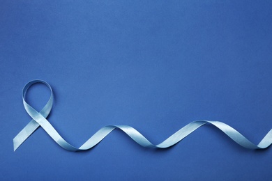 Photo of Blue ribbon on color background, top view with space for text. Colon cancer awareness concept