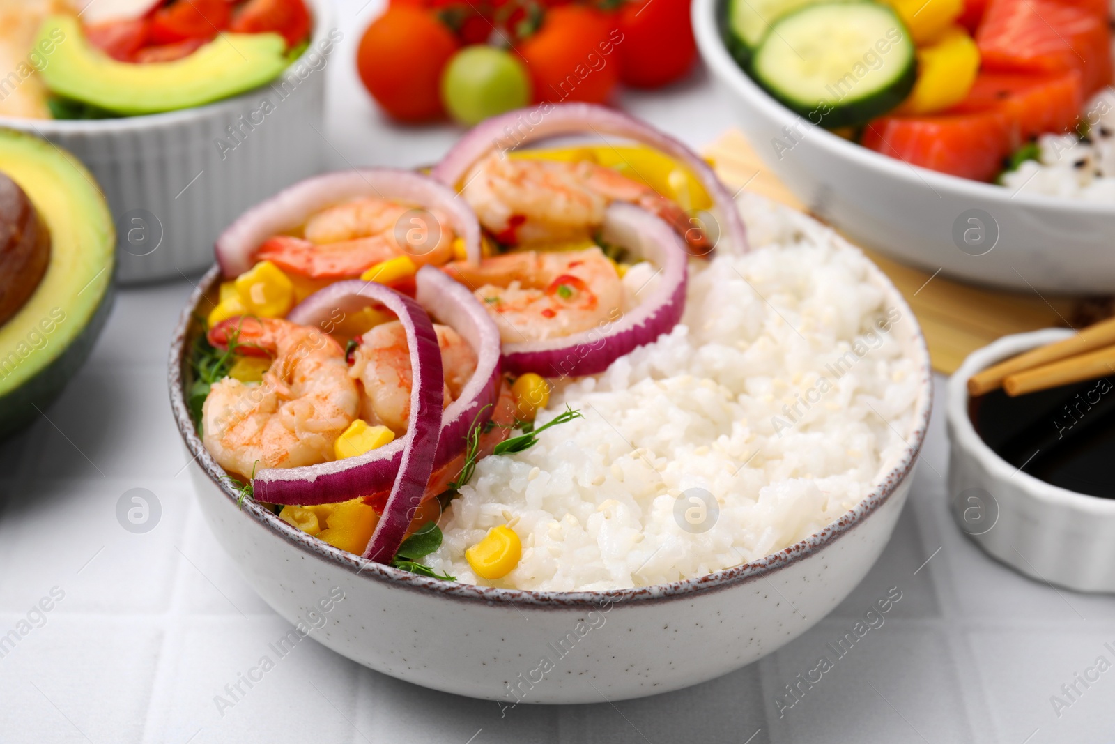 Photo of Delicious poke bowl with shrimps, rice and vegetables on white table, closeup