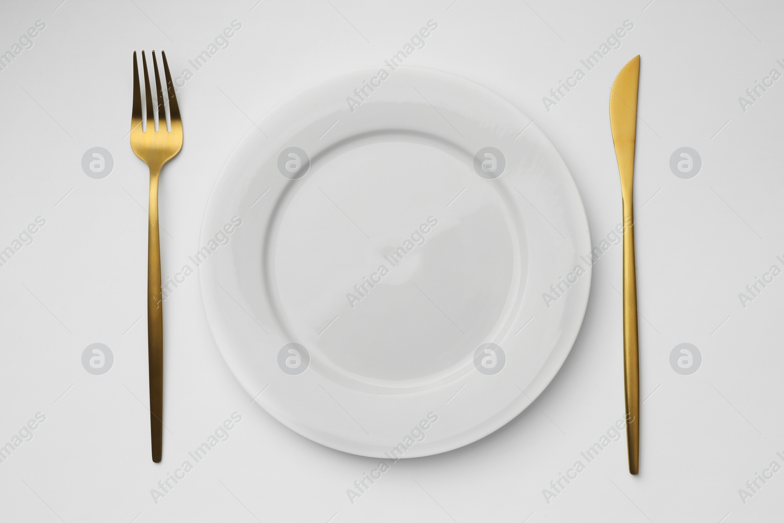 Photo of Empty plate, fork and knife on white background, top view