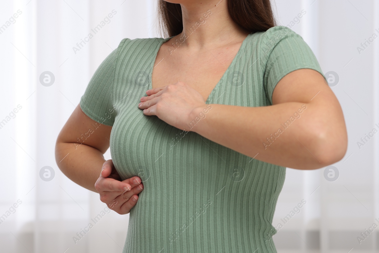 Photo of Mammology. Woman doing breast self-examination indoors, closeup