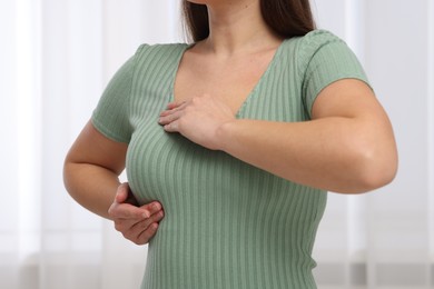 Photo of Mammology. Woman doing breast self-examination indoors, closeup