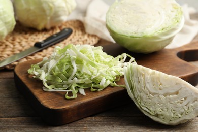 Photo of Fresh shredded cabbage on wooden table, closeup