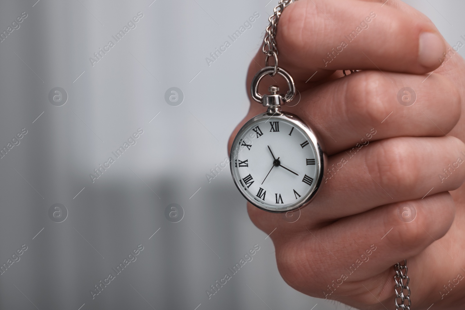 Photo of Man holding chain with elegant pocket watch, closeup. Space for text