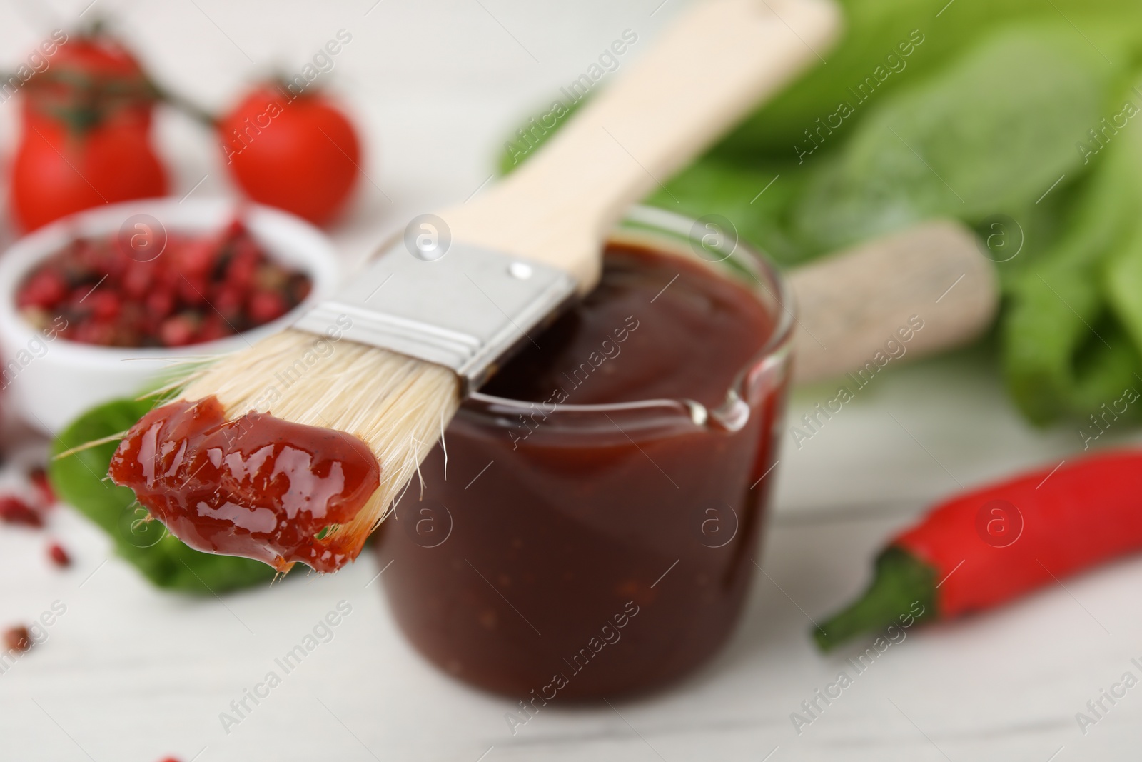 Photo of Marinade and basting brush on white table, selective focus