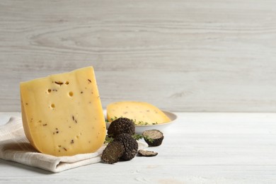 Photo of Delicious cheese, thyme and fresh black truffles on white wooden table. Space for text