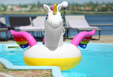 Funny inflatable unicorn ring floating in swimming pool on sunny day, outdoors