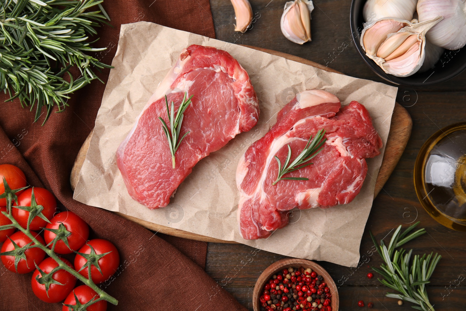 Photo of Fresh raw meat with rosemary, tomatoes and spices on wooden table, flat lay