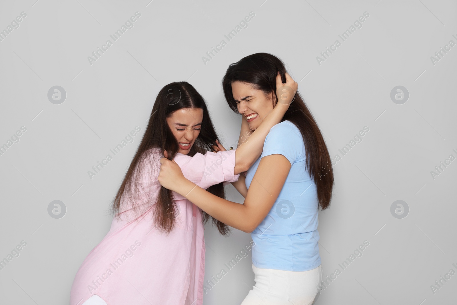 Photo of Aggressive young women fighting on light grey background