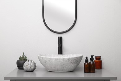 Photo of Dispensers of liquid soap and decor near sink in bathroom