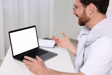 Man having video chat via laptop at white table indoors, selective focus