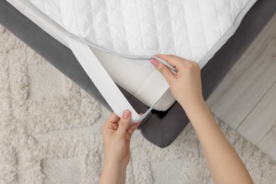 Photo of Woman putting cover on mattress indoors, top view