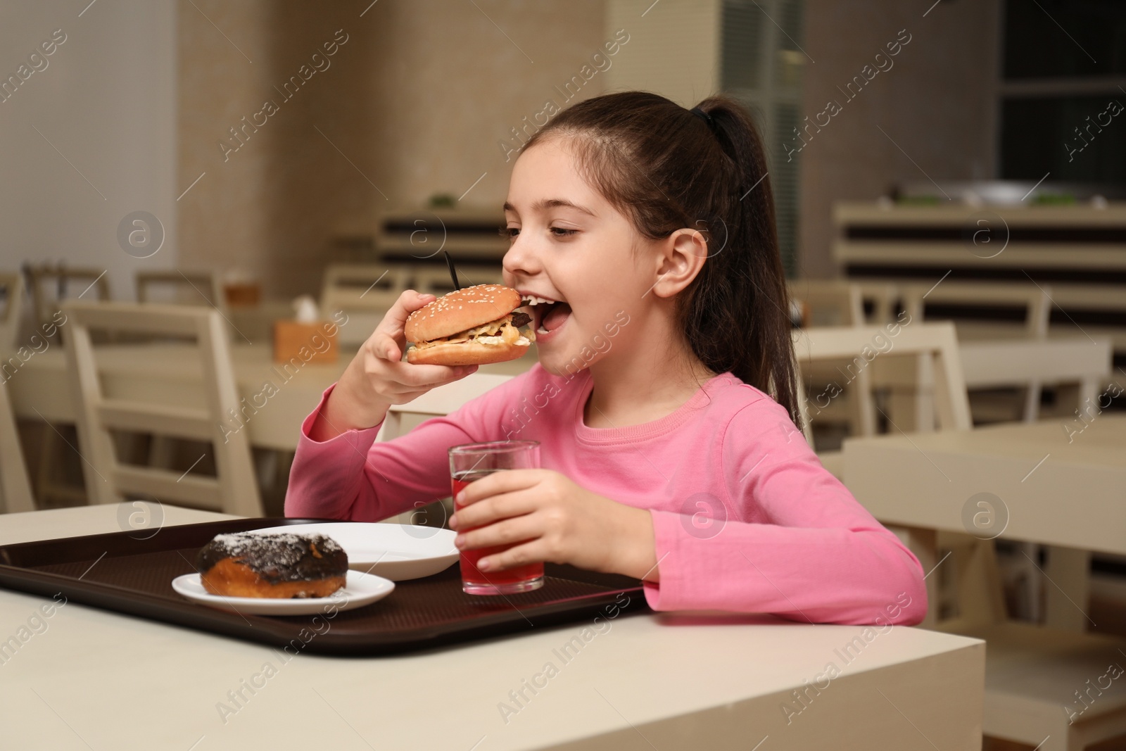 Photo of Little girl with tasty food at table in school canteen