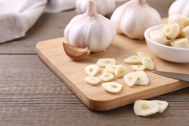 Aromatic cut garlic, cloves and bulbs on wooden table, closeup