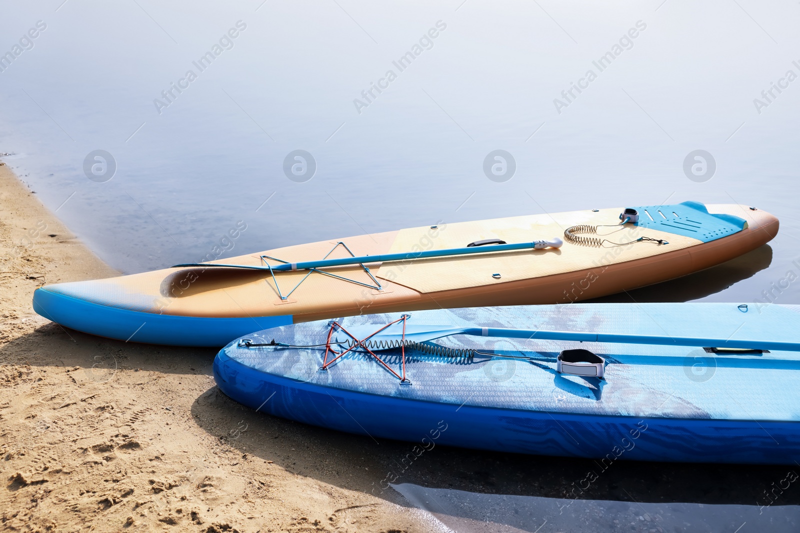 Photo of SUP boards with paddles on river shore