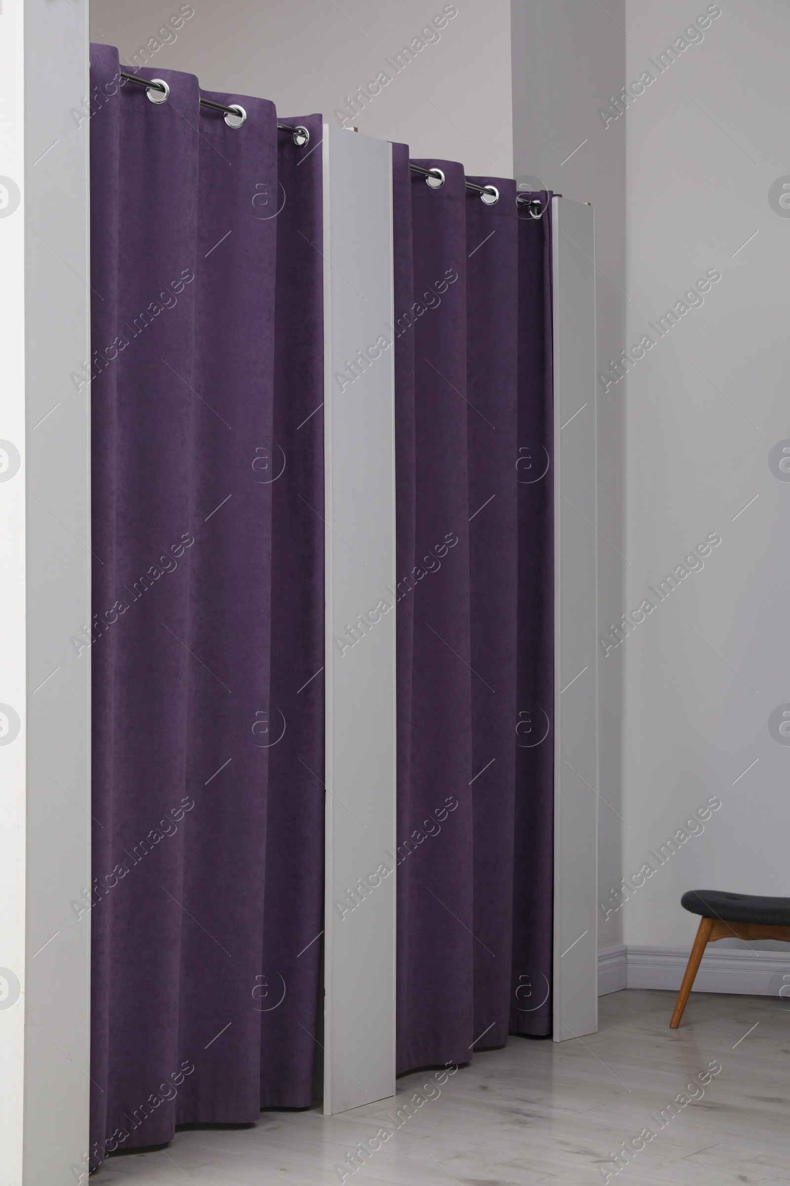 Photo of Dressing rooms with stylish purple curtains in fashion store