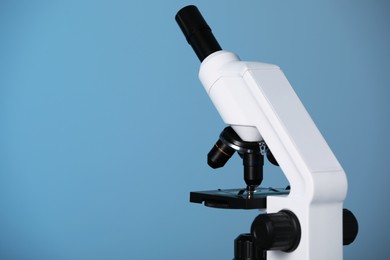 Photo of Modern microscope on blue background. Space for text