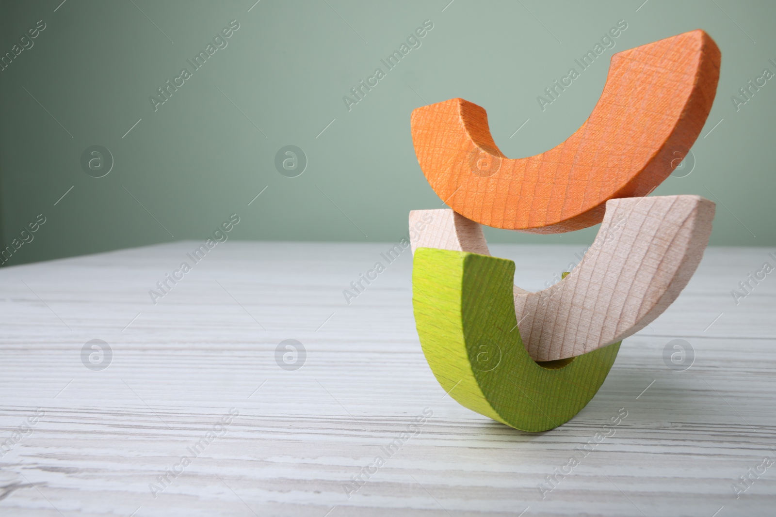 Photo of Colorful wooden pieces of educational toy on light table, closeup and space for text. Motor skills development