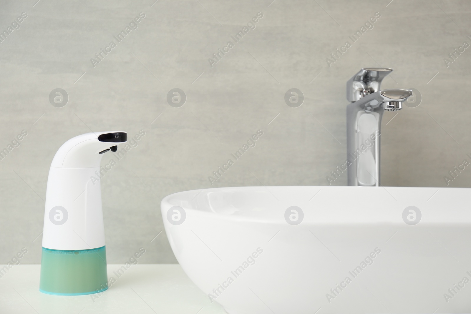 Photo of Modern automatic soap dispenser near sink in bathroom, closeup