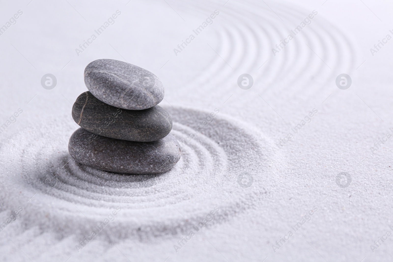 Photo of Zen garden stones on white sand with pattern, space for text