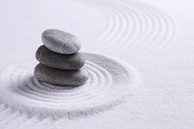 Photo of Zen garden stones on white sand with pattern, space for text