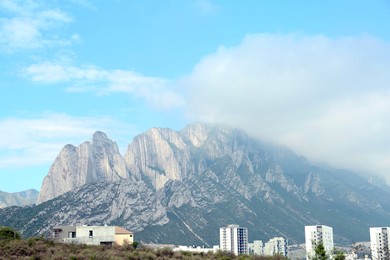 City near mountains under blue sky with clouds