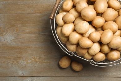 Raw fresh organic potatoes on wooden background, top view. Space for text