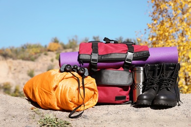 Set of camping equipment with sleeping bag on ground outdoors