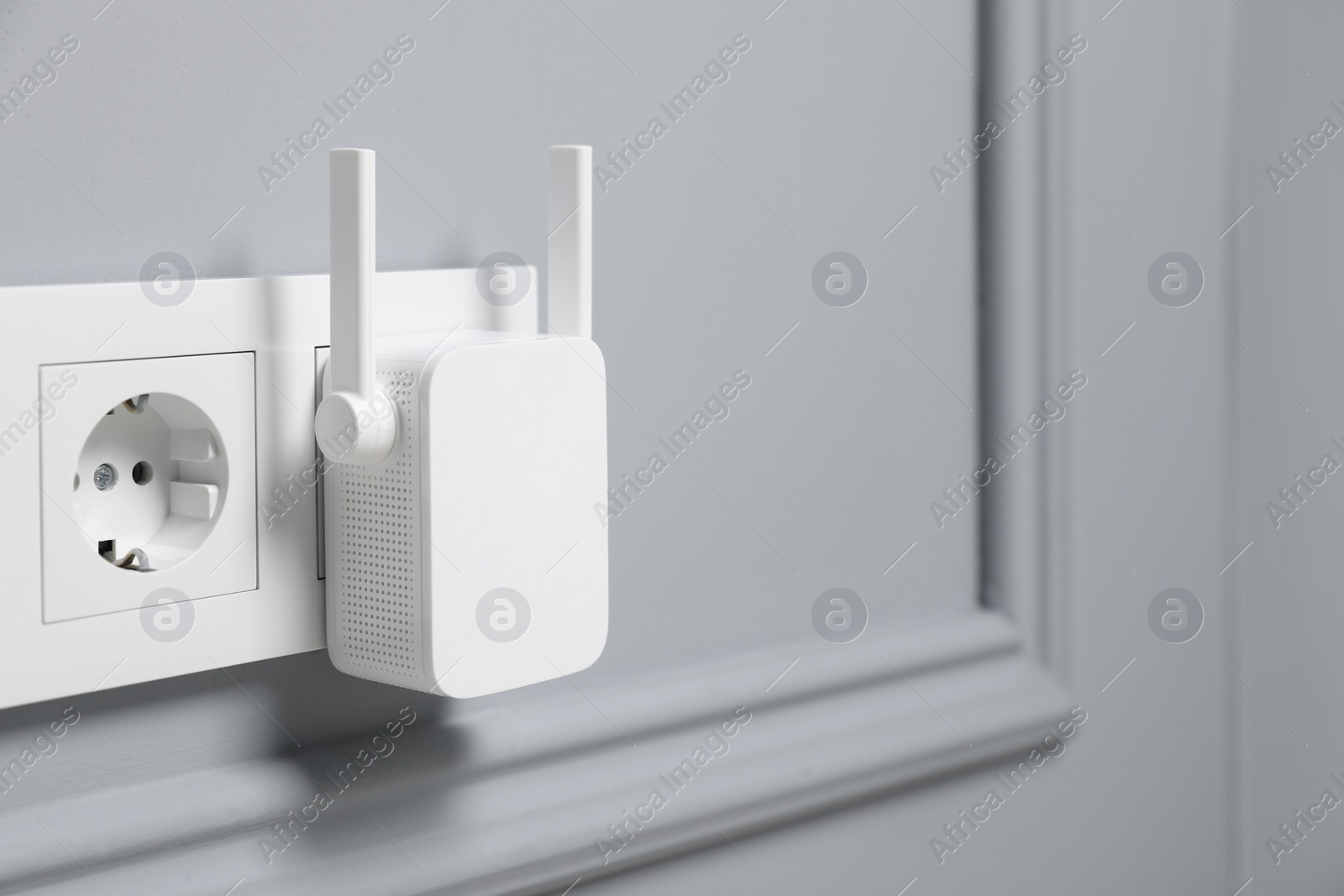 Photo of Wireless Wi-Fi repeater on light grey wall, space for text