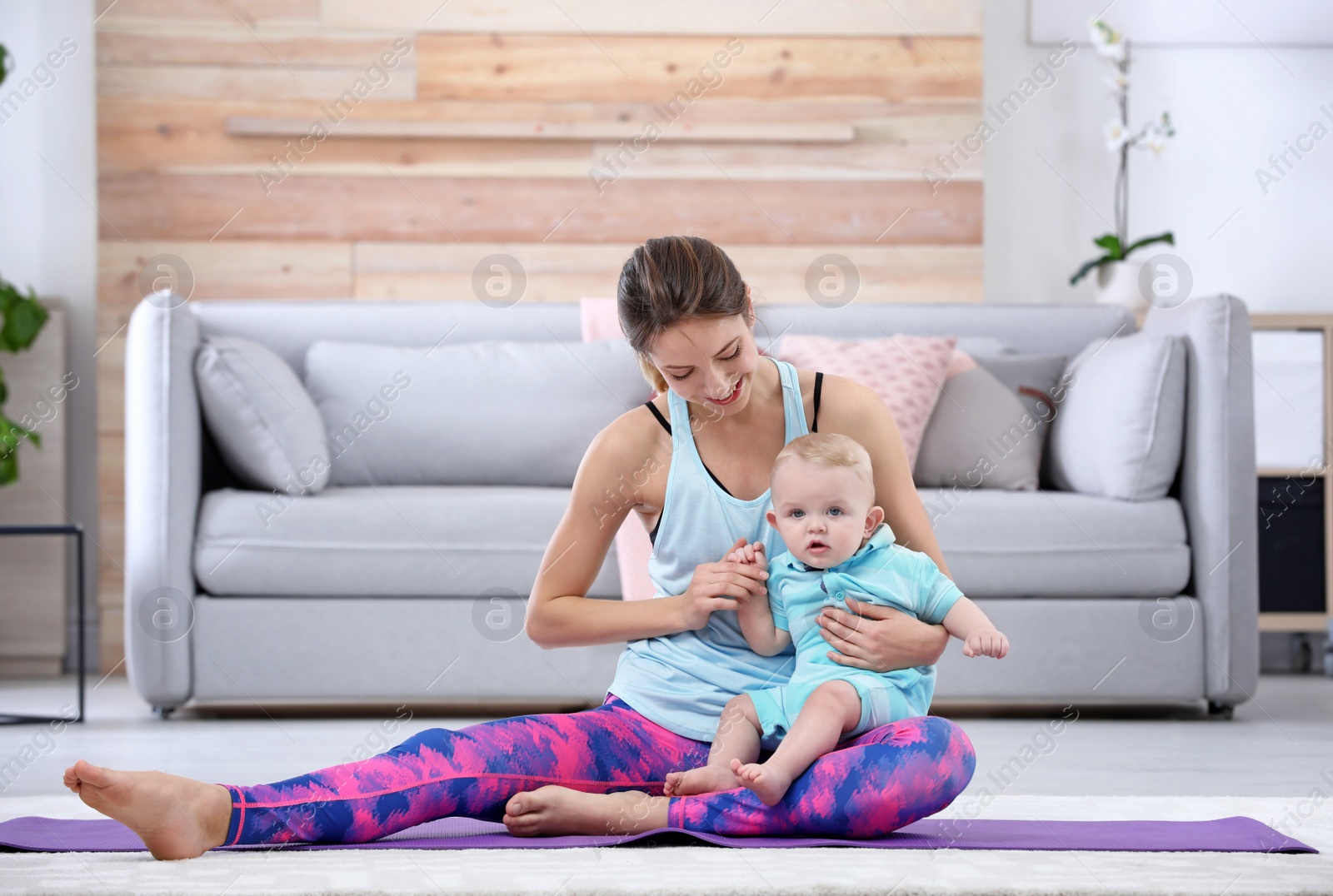 Photo of Young sportive woman doing exercise with her son at home. Fitness training