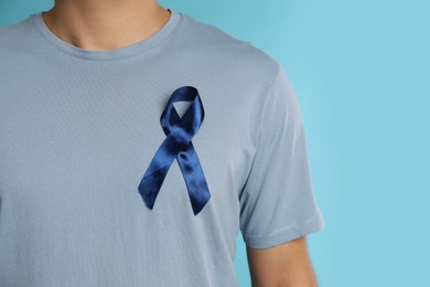 Man with ribbon on light blue background, closeup. Urology cancer awareness