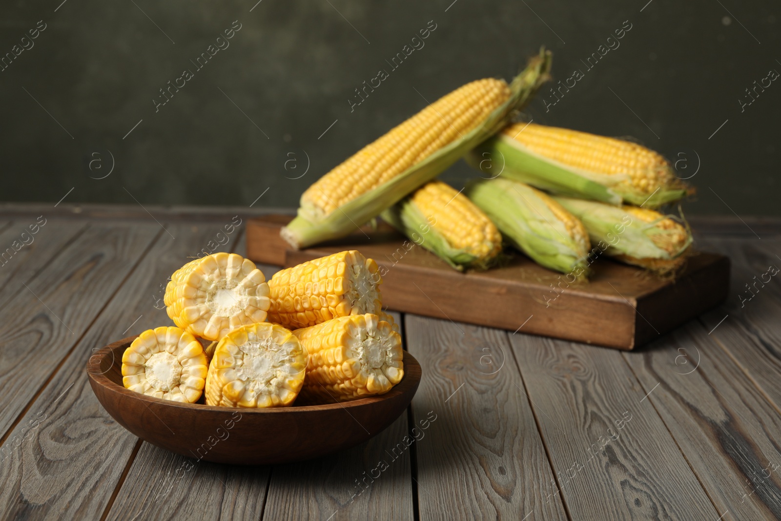 Photo of Tasty sweet corn cobs on wooden table. Space for text