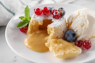 Photo of Tasty vanilla fondant with white chocolate, berries and ice cream on table, closeup