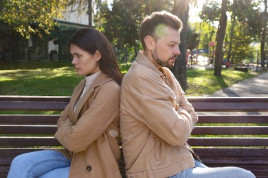 Photo of Upset arguing couple sitting on bench in park. Relationship problems