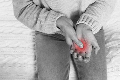 Image of Woman suffering from trigger finger, closeup. Black and white photo with red accent
