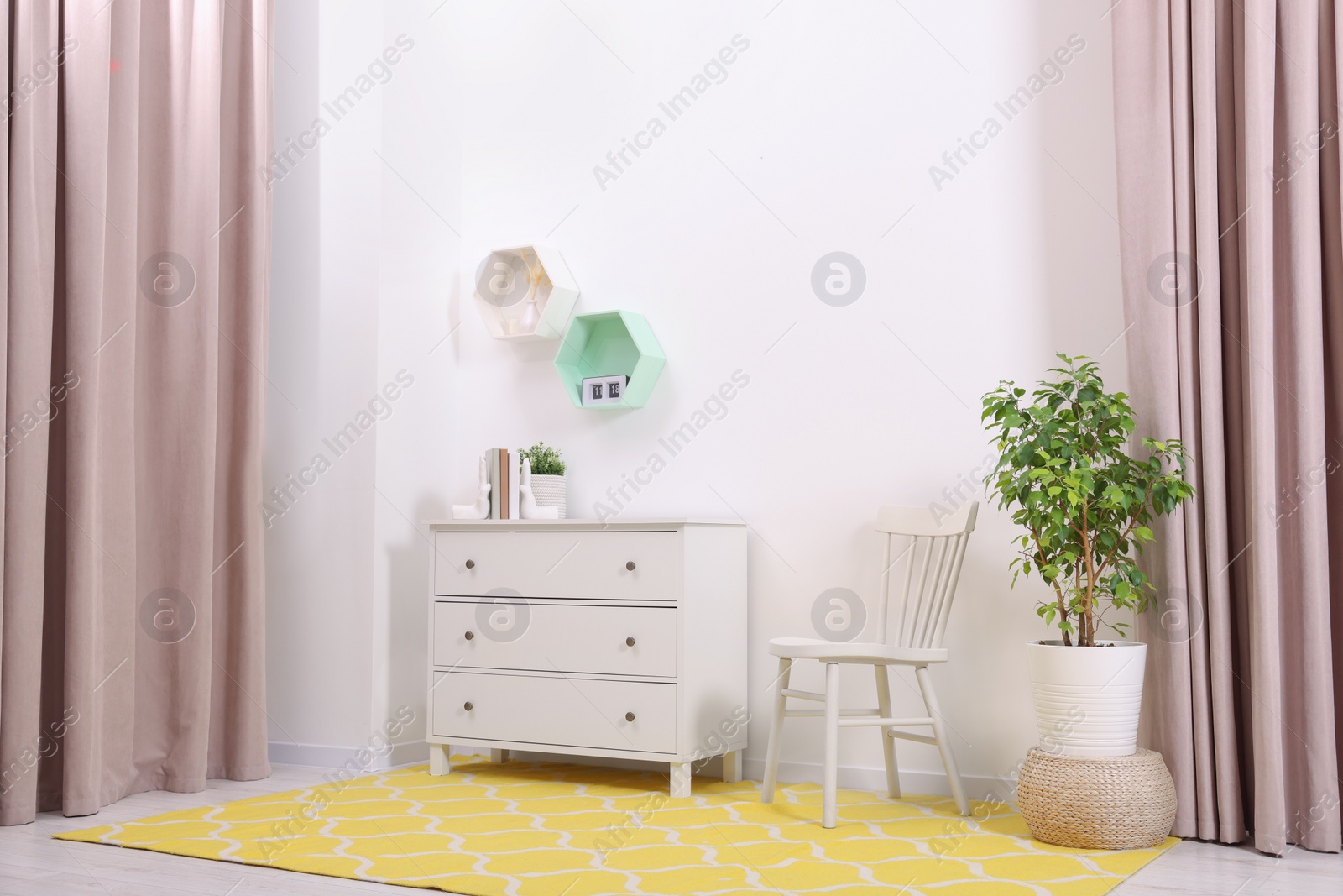 Photo of Stylish room interior with chest of drawers, yellow rug and chair indoors