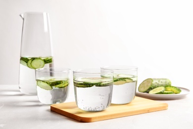 Photo of Glasses and jug of fresh cucumber water on table