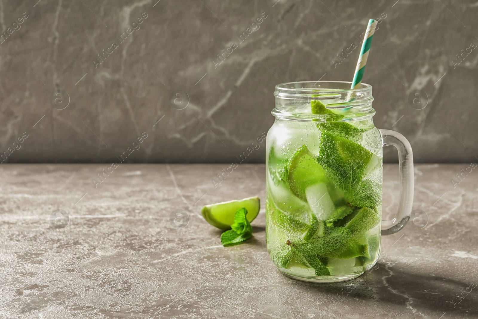 Photo of Refreshing beverage with mint and lime in mason jar on table