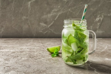 Refreshing beverage with mint and lime in mason jar on table