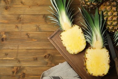 Whole and cut pineapples on wooden table, flat lay. Space for text