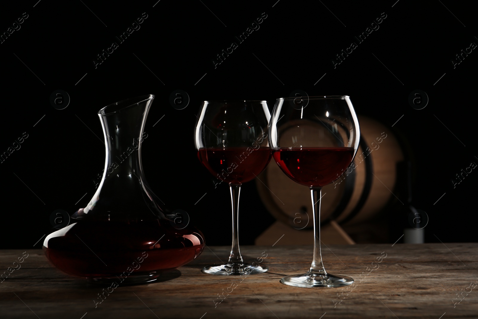 Photo of Elegant decanter and glasses with red wine on table against dark background
