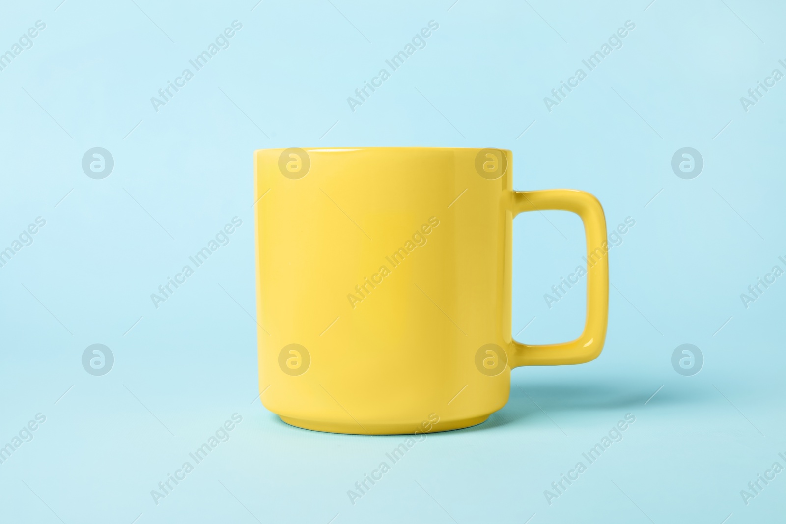 Photo of One yellow ceramic mug on light blue background