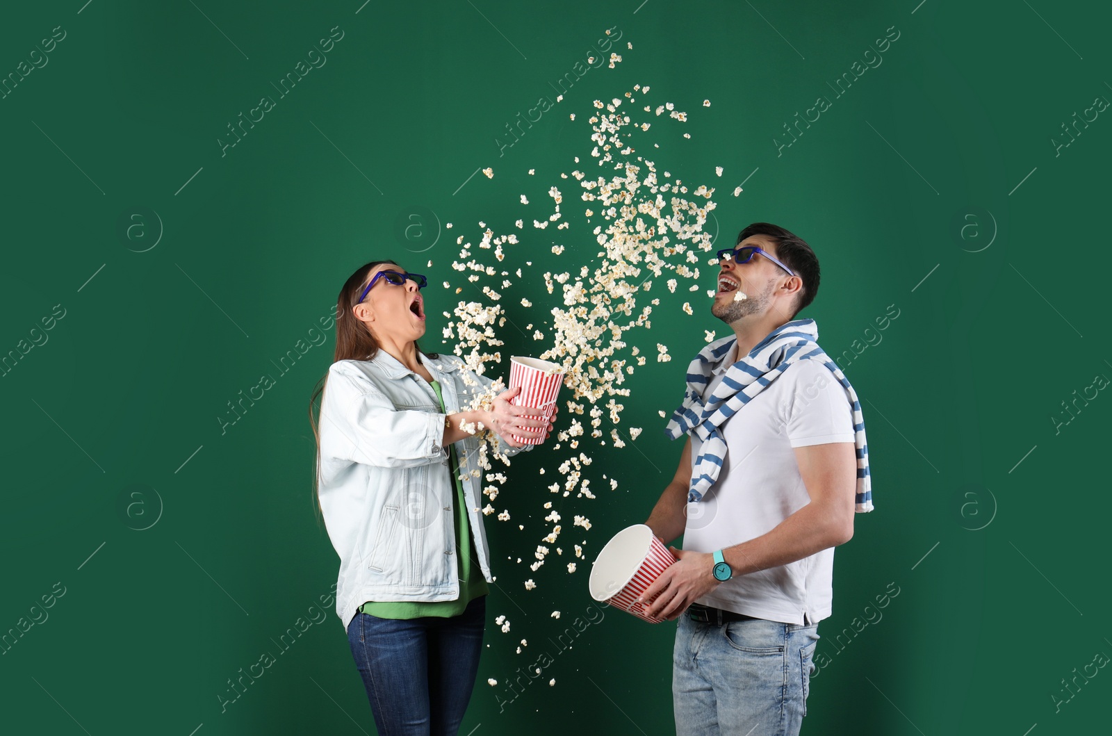 Photo of Emotional couple with 3D glasses throwing popcorn on color background