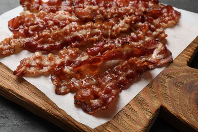 Photo of Slices of tasty fried bacon on black table, closeup